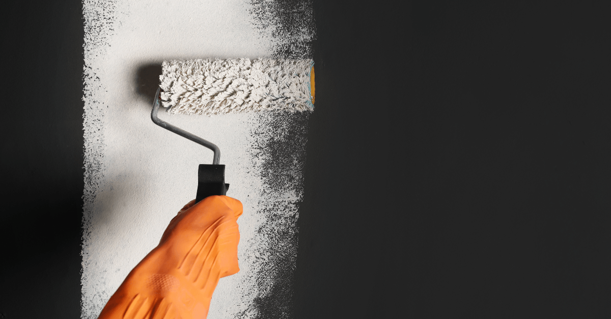 Person painting a black wall with white paint