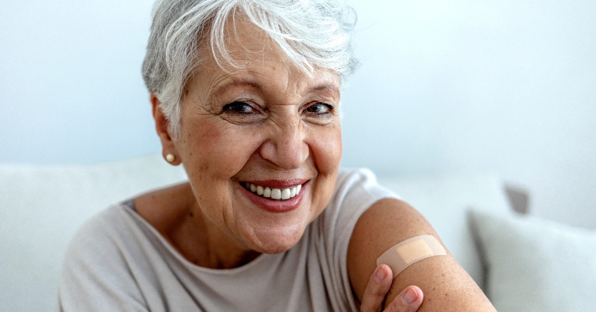 proud mature woman smile after vaccination with bandage on arm