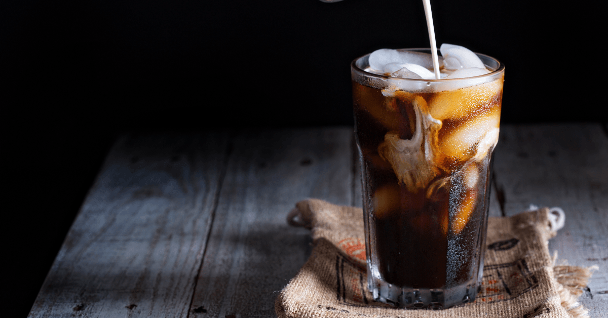 Milk pouring into glass of iced coffee