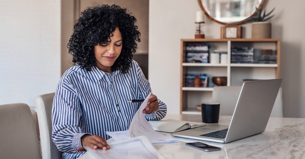 Smiling female entrepreneur going through paperwork at her dining table