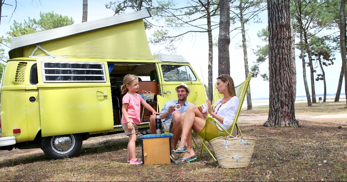 happy family relaxing by camper van in summer