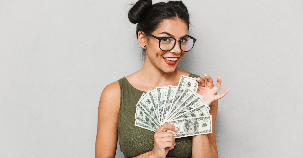 cheerful young woman showing dollars