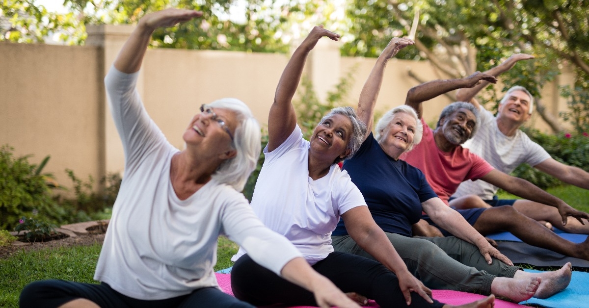 senior people with arms raised exercising at park