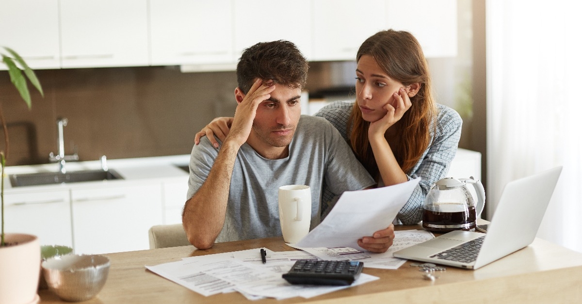 young Caucasian couple calculating family budget in kitchen