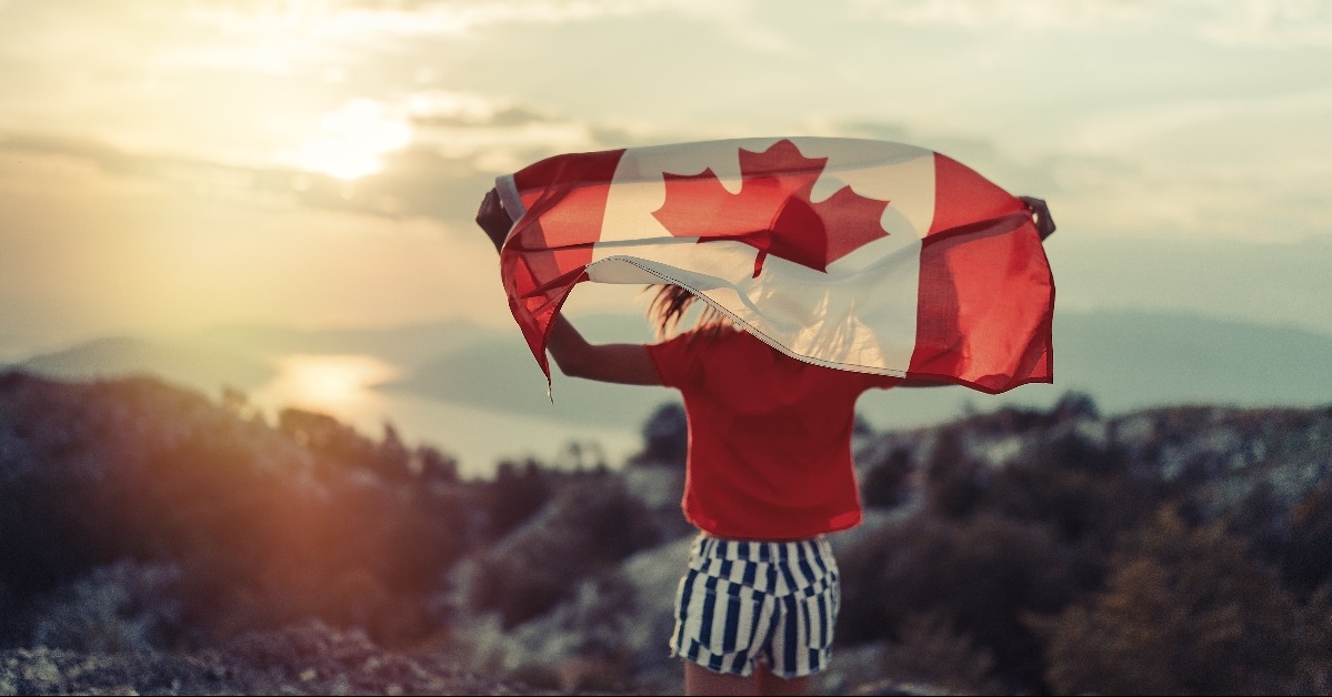happy child teenage girl waving the flag of Canada while running at sunset