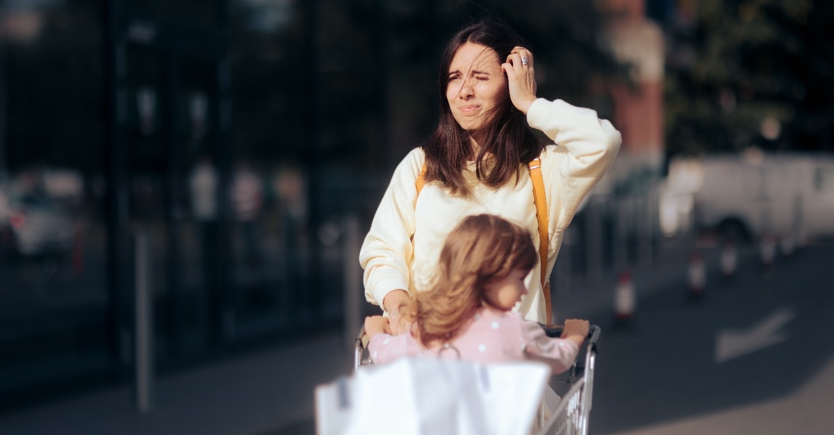 stressed mom with wind in her hair pushing shopping cart