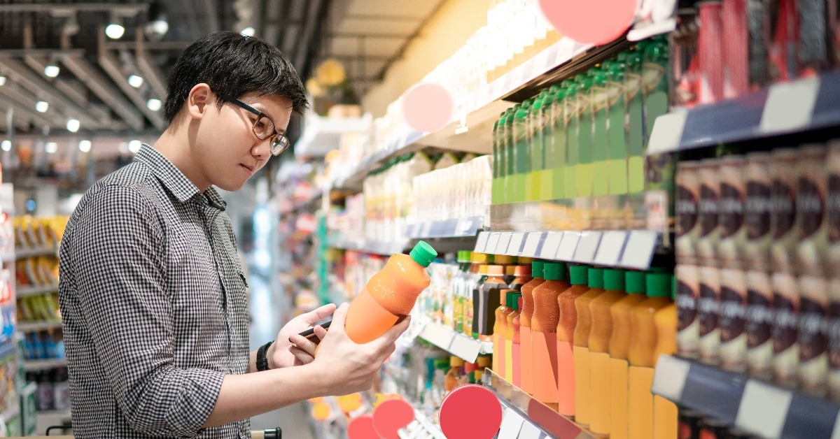 asian man choosing orange juice in supermarket