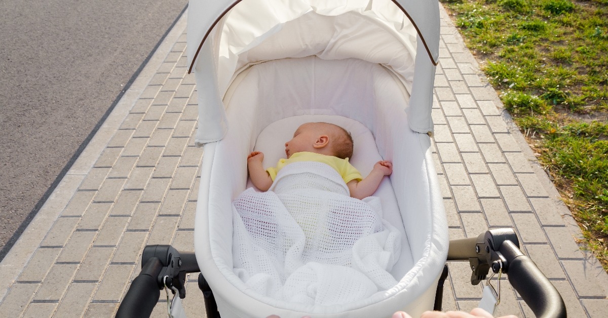 mother hands pushing white baby stroller