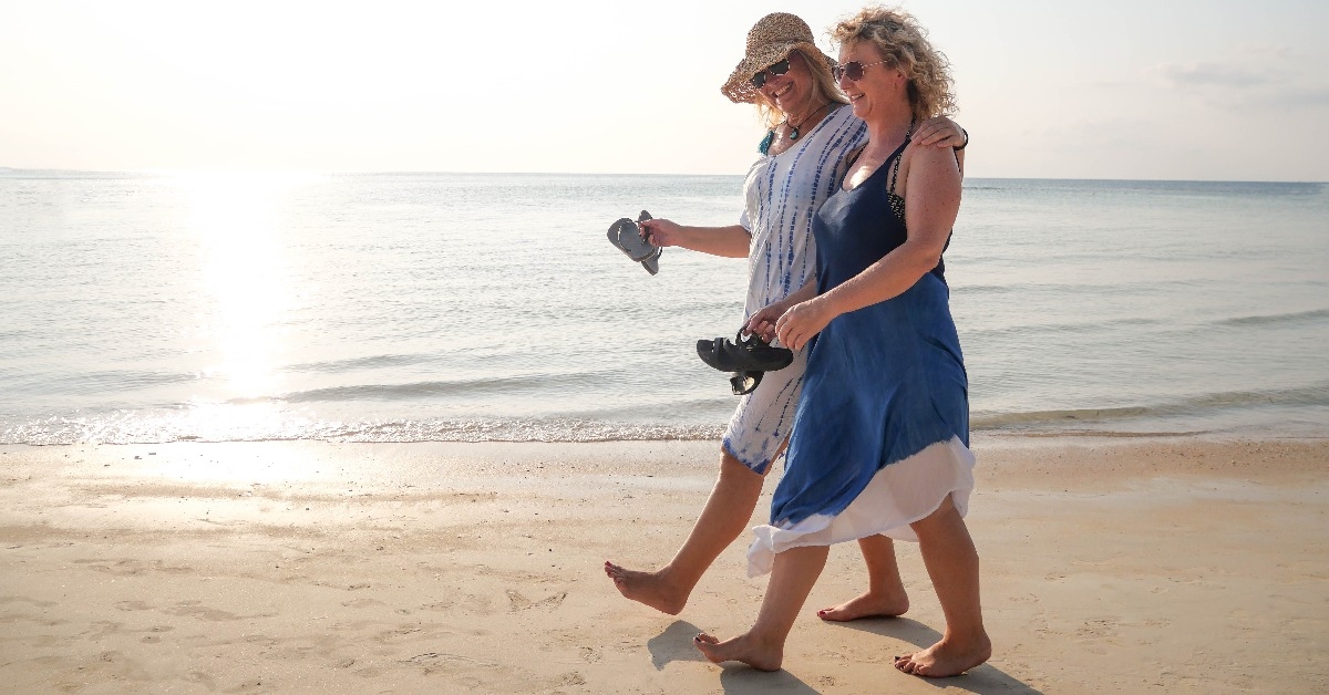 two funny older women walking and laughing at coast line