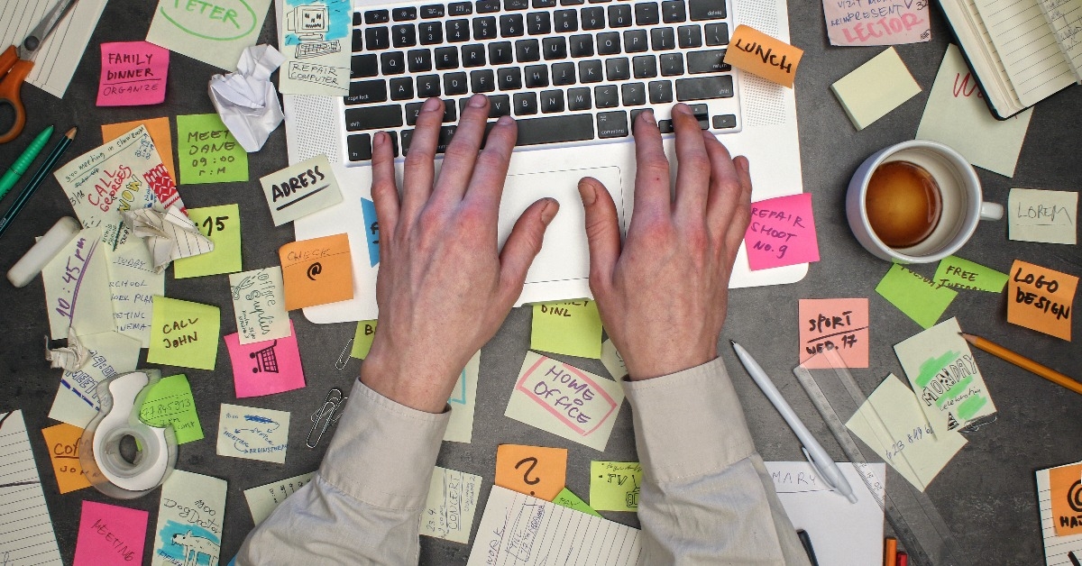 top view on man working on laptop computer with post it notes