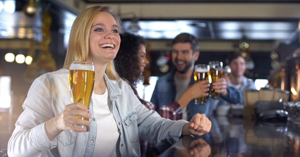 Happy friends raising glasses of beer in bar