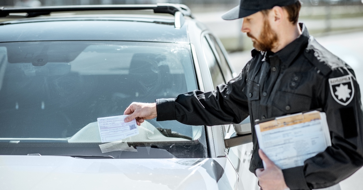 man putting parking ticket on car