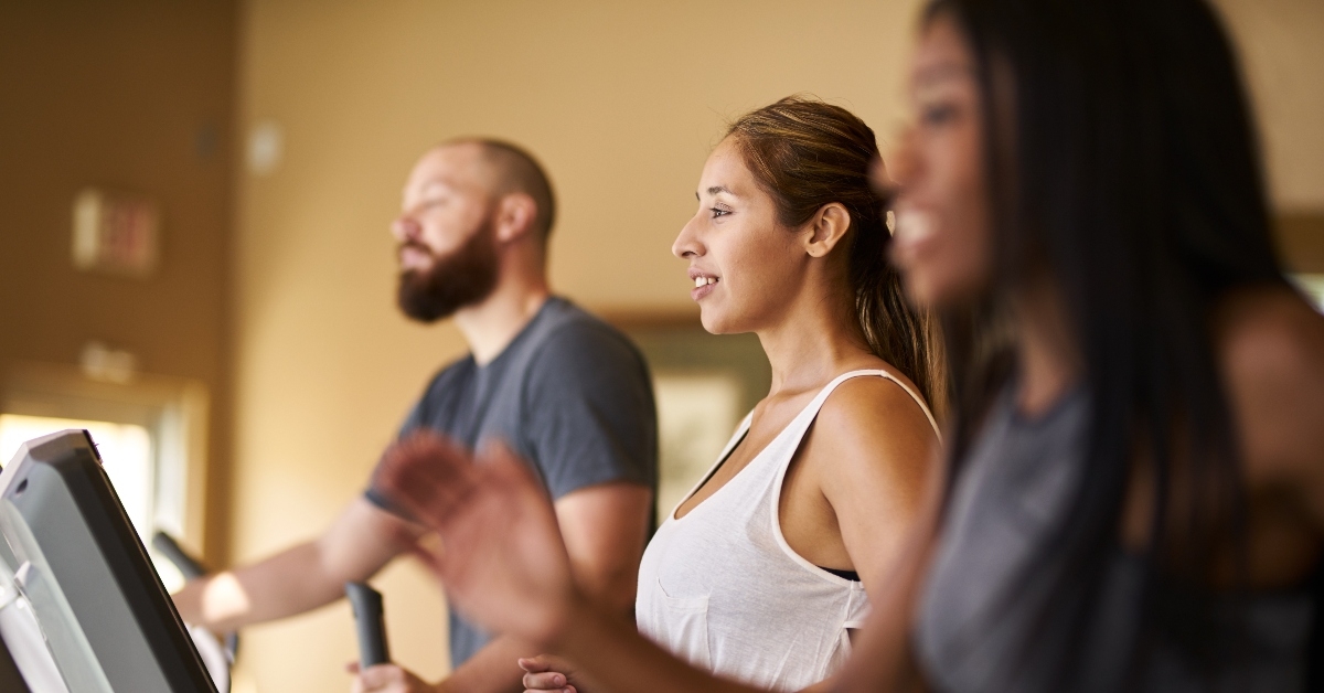 Three people running on treadmills at the gym