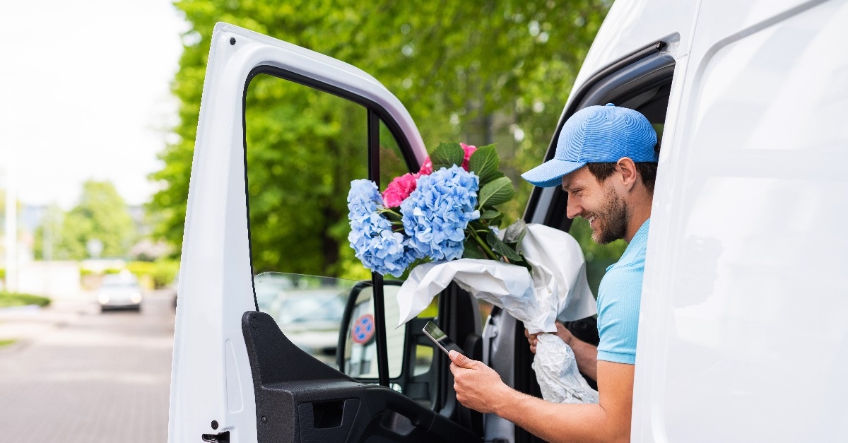 happy courier with a tablet PC during flowers delivery