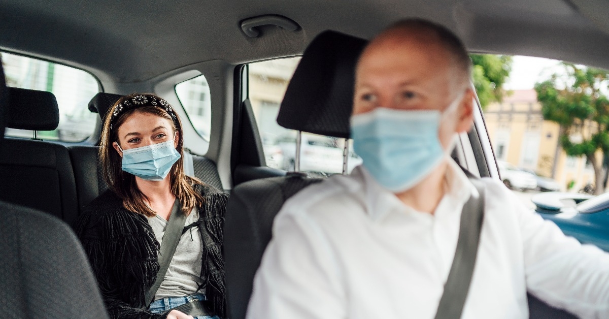 taxi driver in a mask with a client on the back seat wearing mask