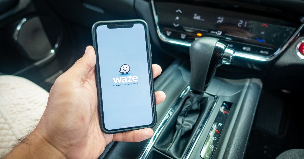 a man holding the iPhone X with Waze navigation app inside the car