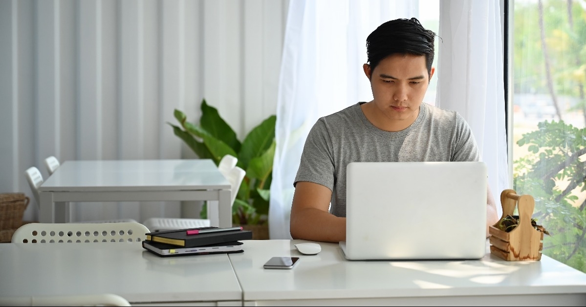 asian man using laptop computer at cafe