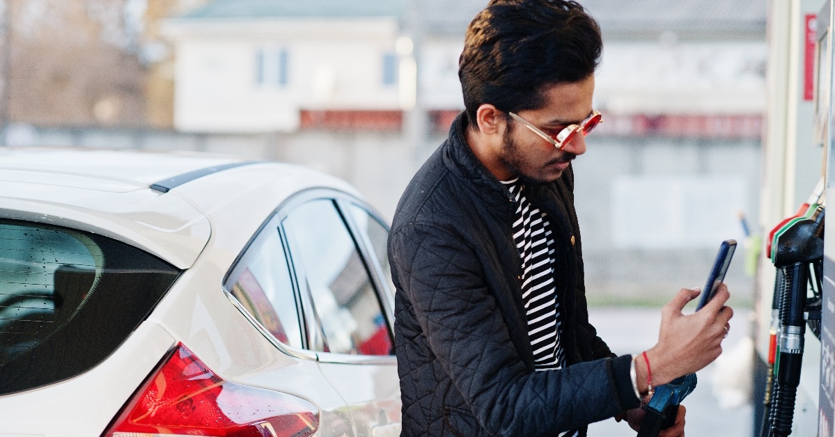 indian male refueling his white car on gas station