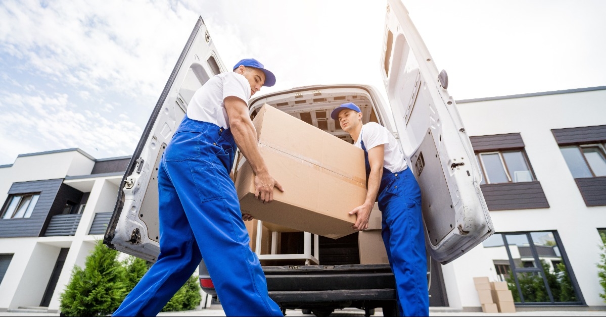two removal company workers unloading boxes and furniture from minibus
