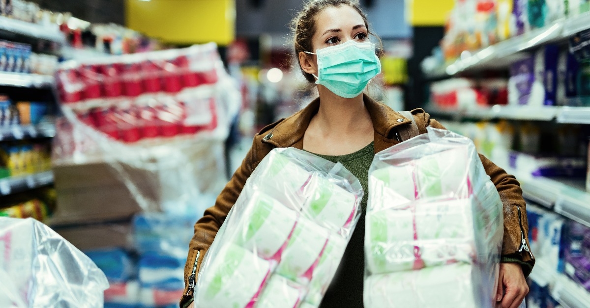 woman with face mask buying toilet paper in supermarket