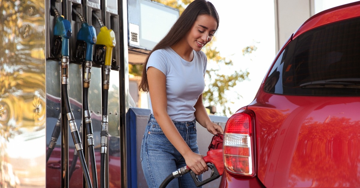 young woman refueling car at self service gas station