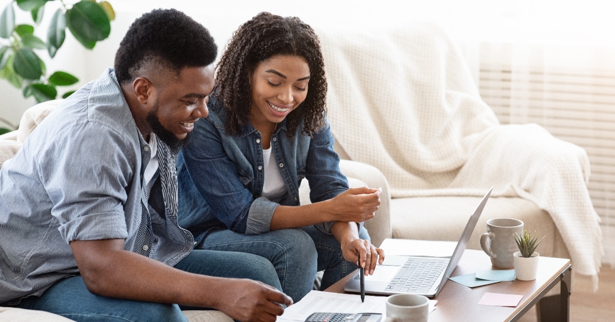 smiling black couple discussing total amount of their spends at home