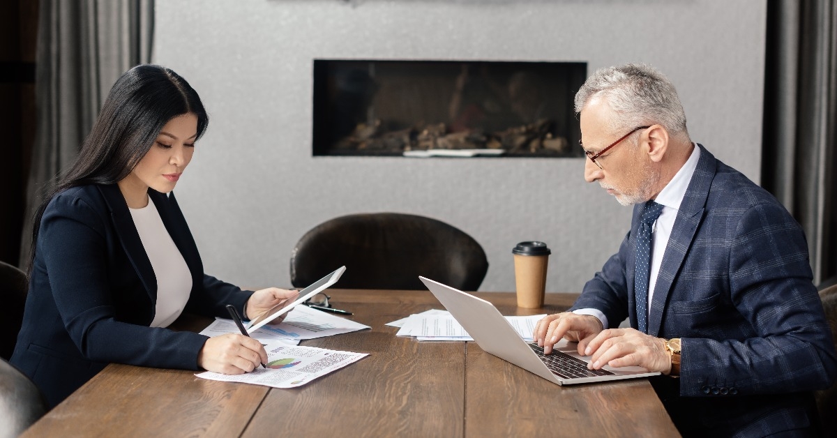 businessman using laptop and asian businesswoman doing paperwork