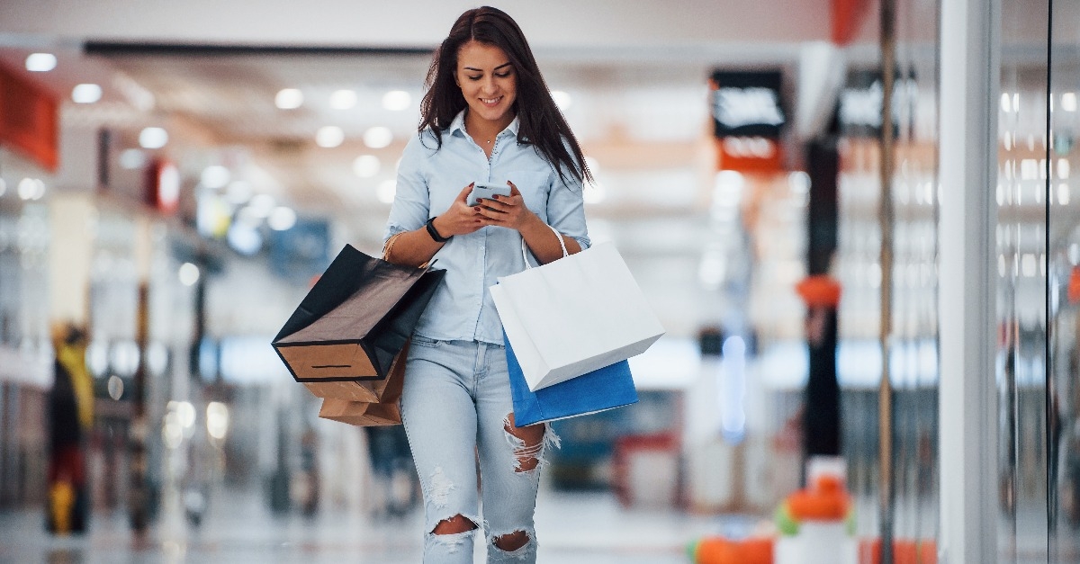 brunette woman in the supermarket with shopping bags and phone in hands
