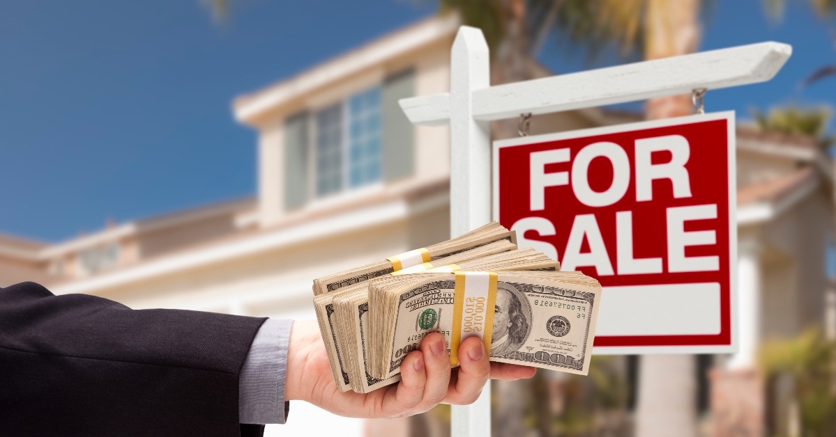 buyer handing over cash for house with for sale sign