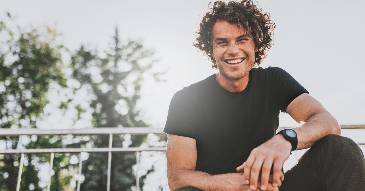 happy stylish young man wears black t-shirt and wristwatch on the street