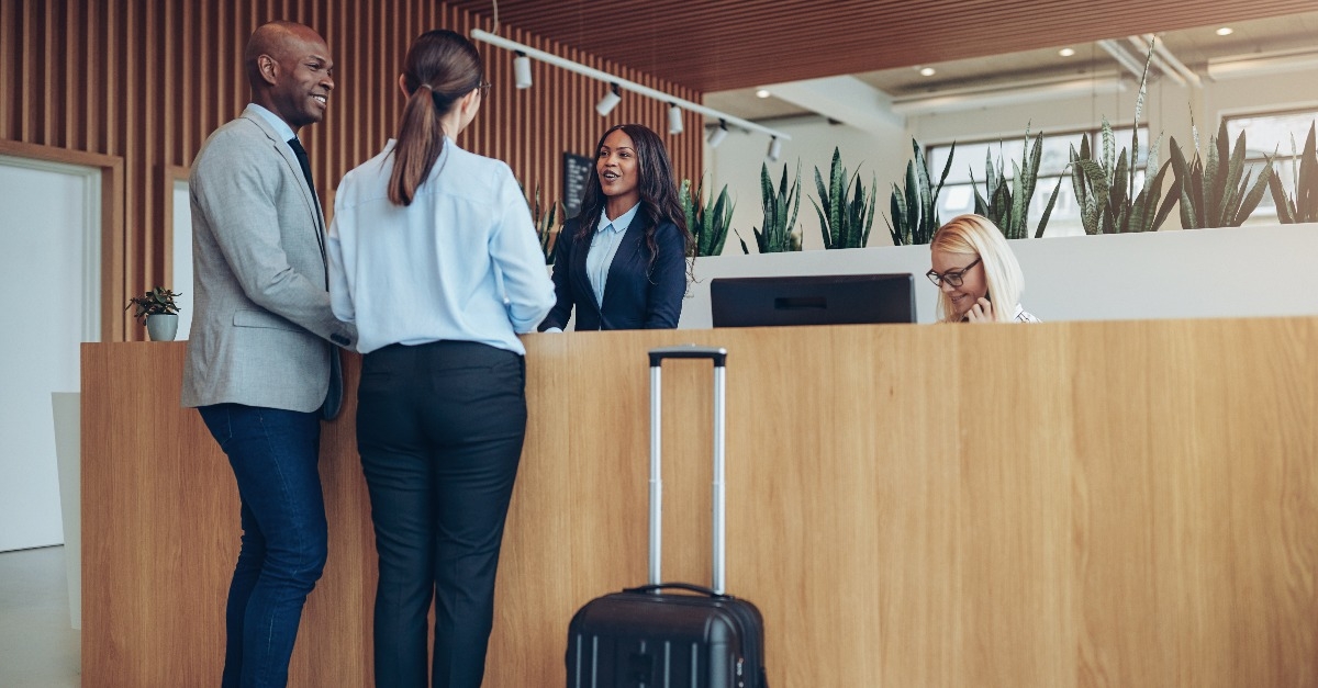 two smiling guests checking in at a hotel reception