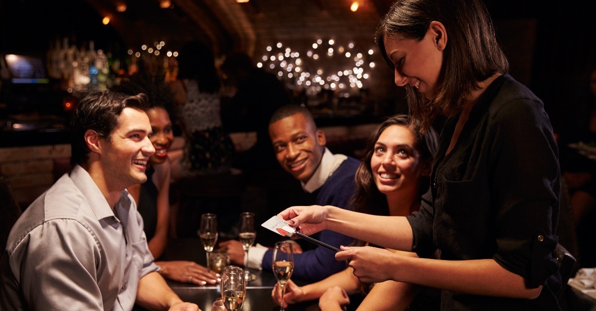 waitress takes payment for restaurant bill on digital tablet