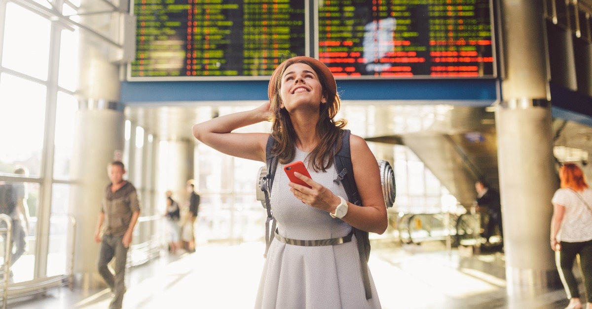 young caucasian woman in dress and backpack standing inside train station