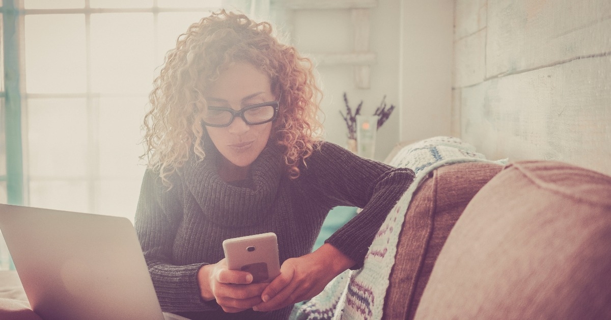  woman sitting on the sofa with phone device and laptop computer working
