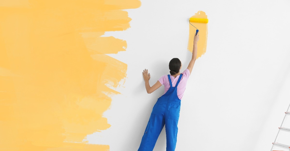 young female decorator painting wall