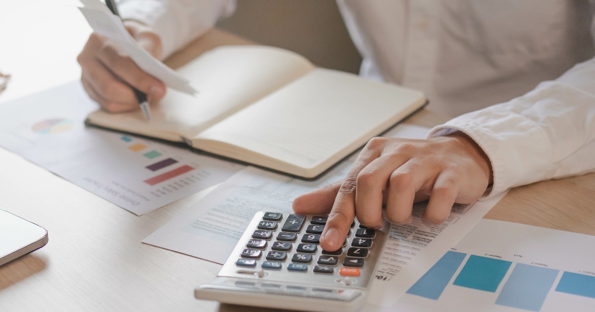 male is pressing a calculator to calculate tax income and expenses