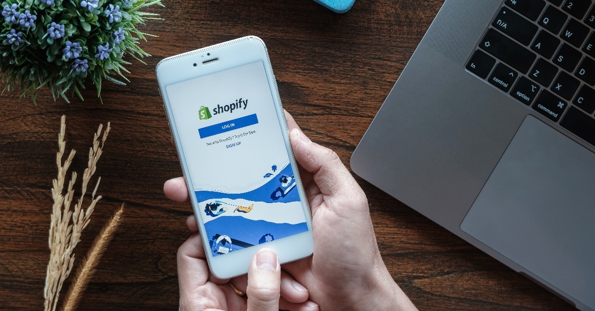 male holds iphone 6s with shopify application