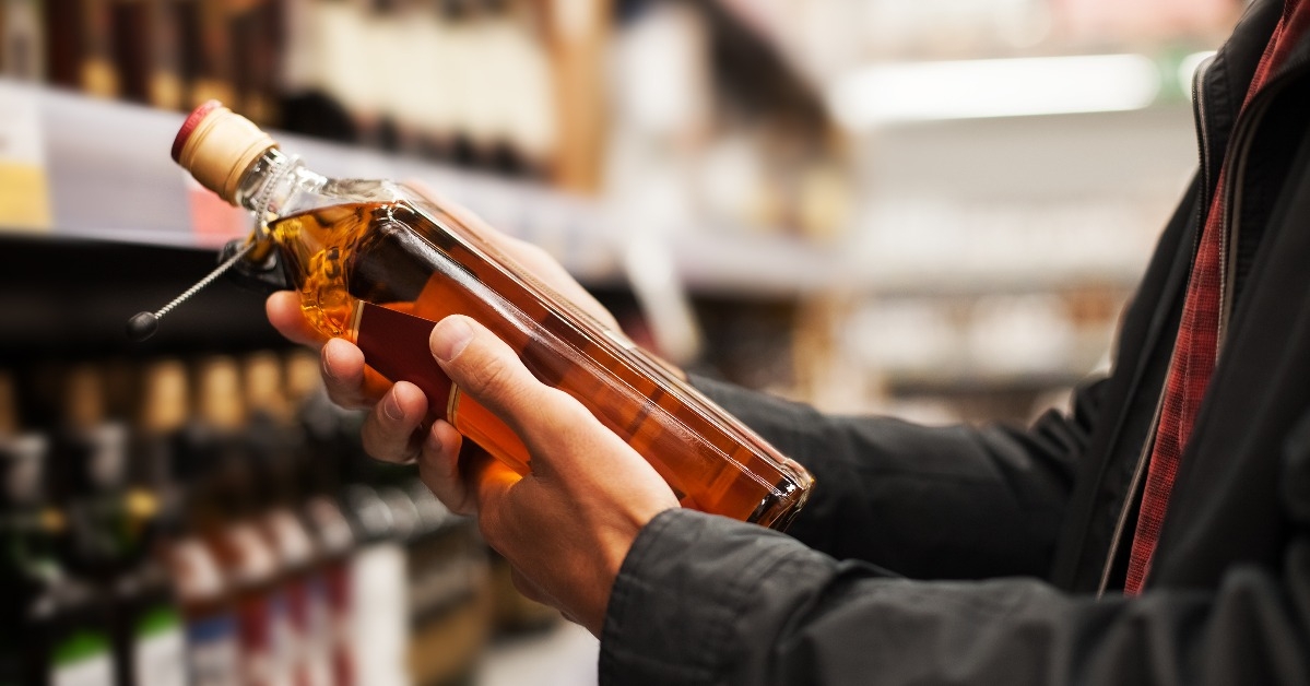a man takes alcoholic drinks from the supermarket shelf