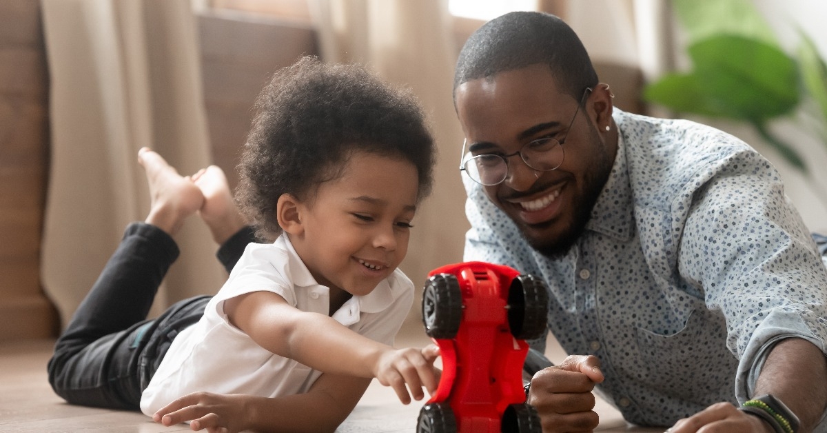 cute little african kid son playing toy car with dad