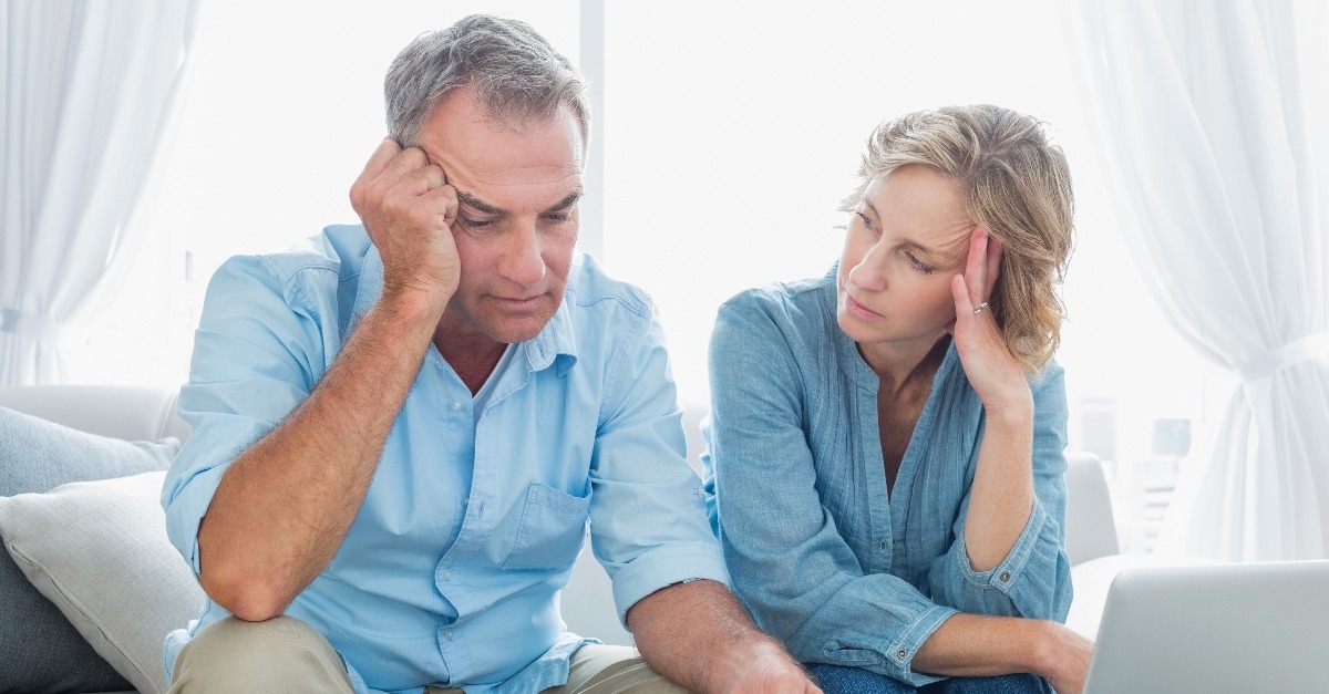 worried couple using their laptop to pay their bills