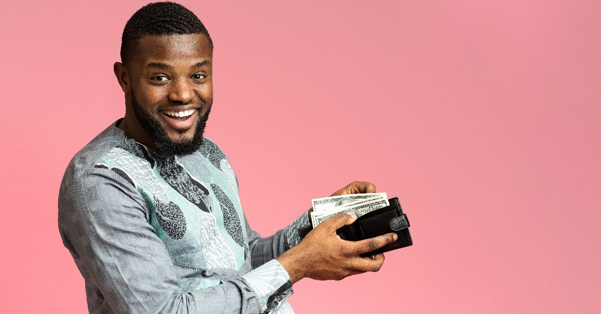 excited man putting money into wallet