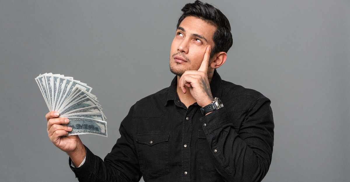 young man thinking while holding money