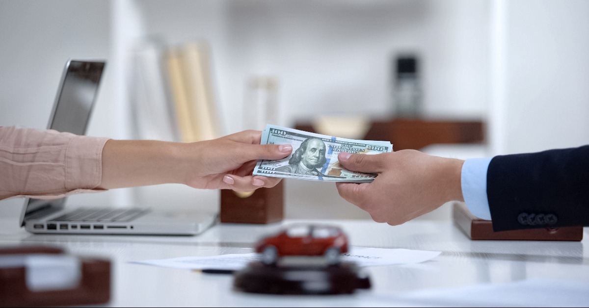 female giving dollars to car dealer