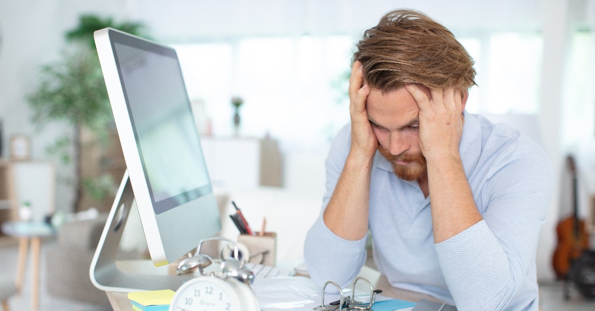 stressed businessman at his desk with head in his hands