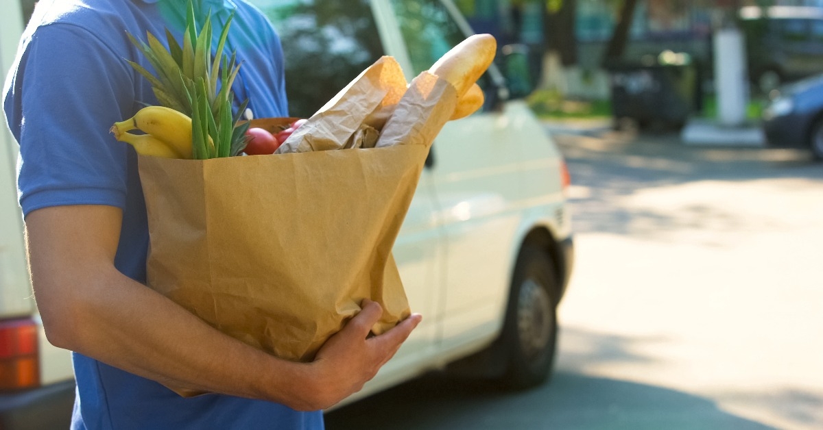 delivery worker holding grocery bag with fresh tasty goods