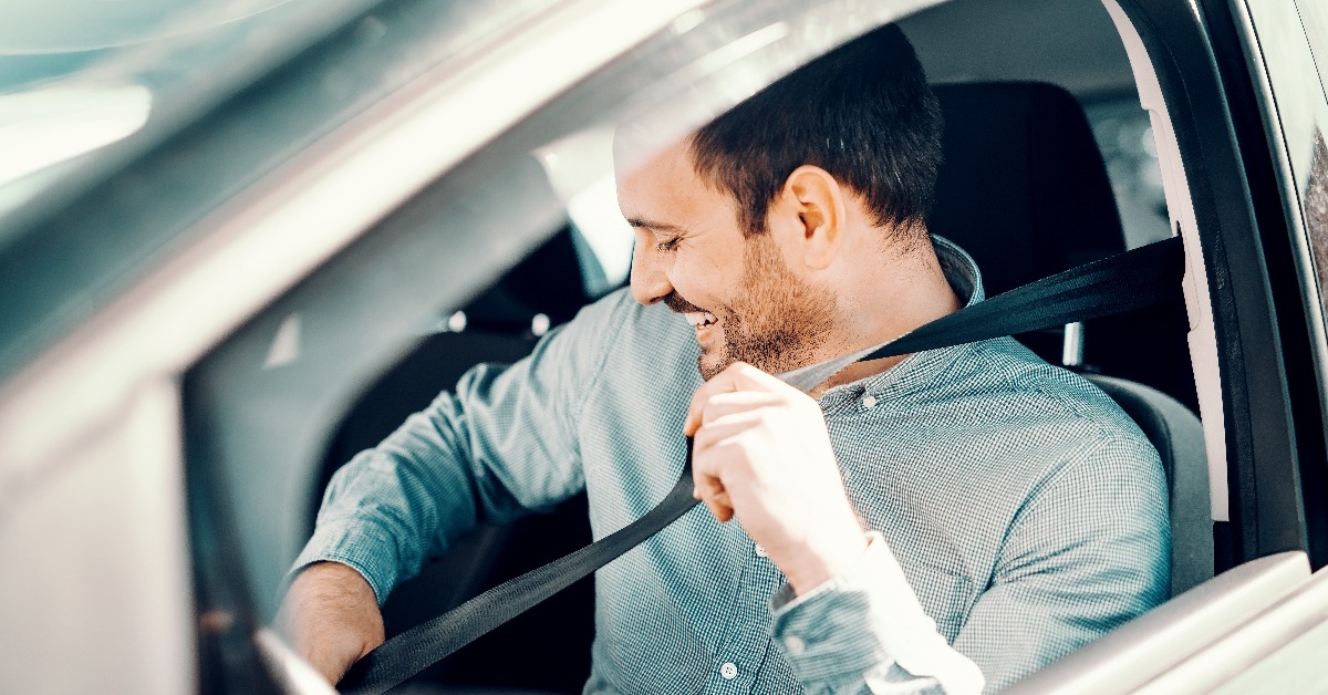  smiling man fastening seat belt