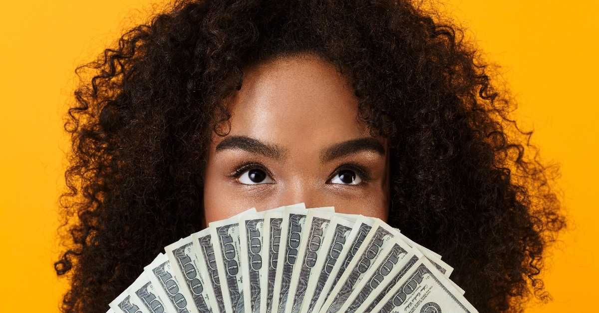 woman holding money covering face