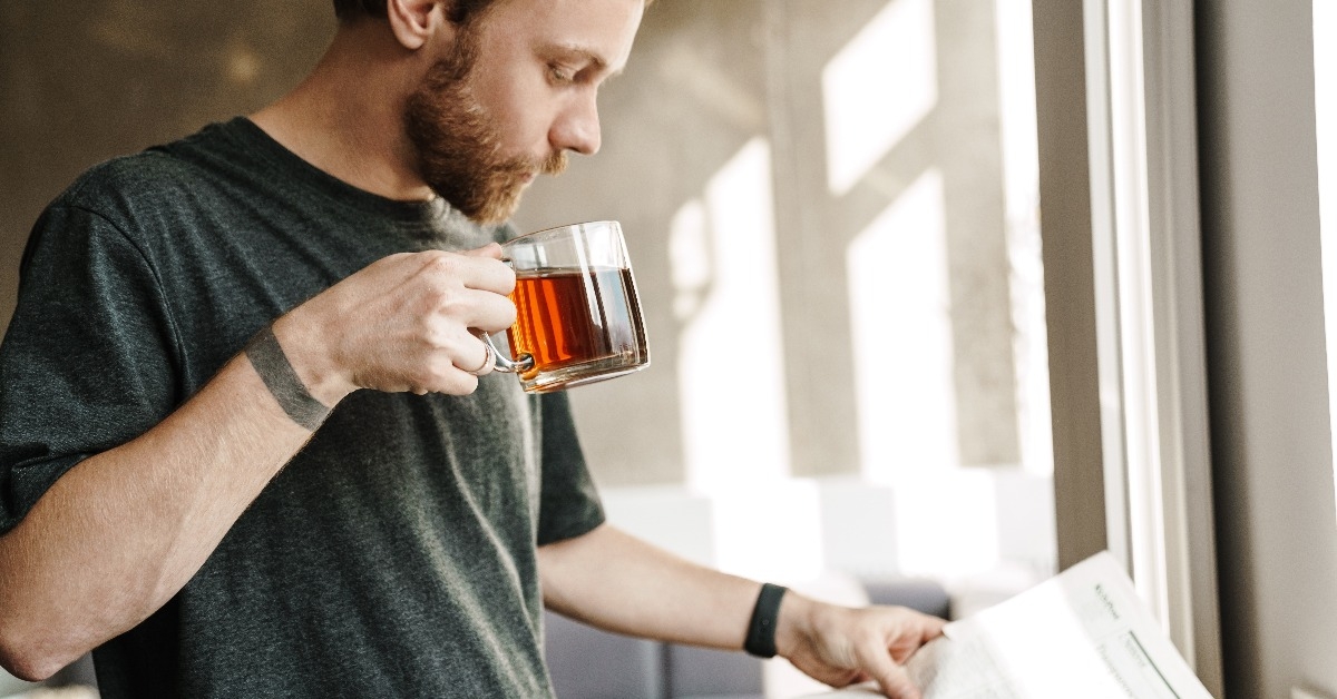 man reading newspaper while drinking tea