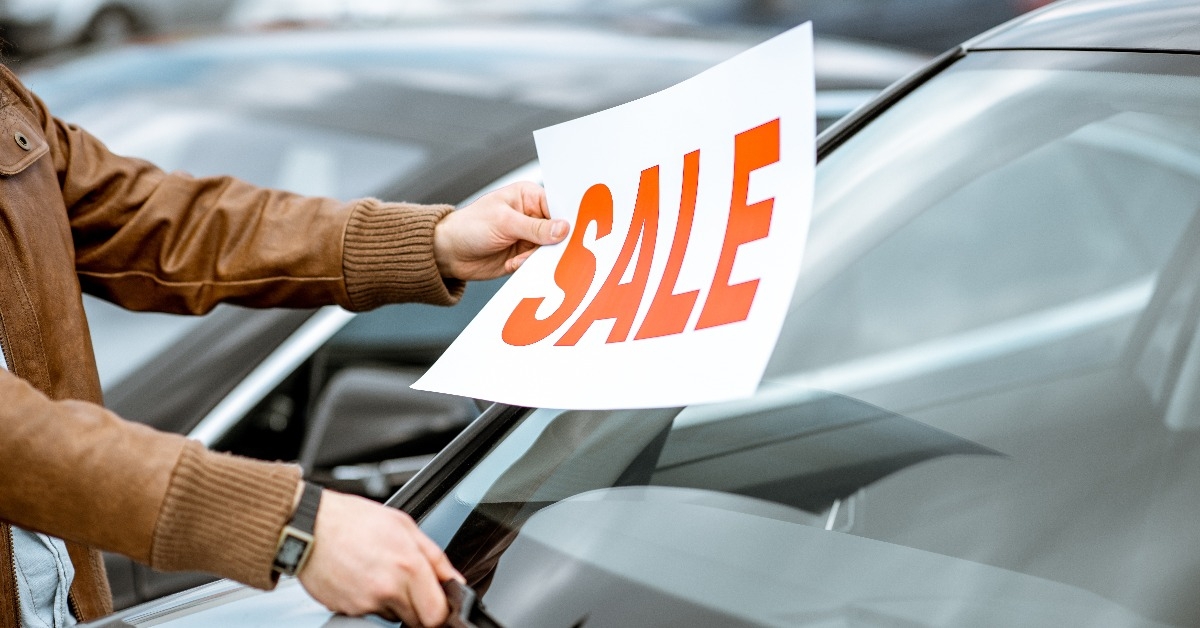 salesperson putting sale plate on the car windshield
