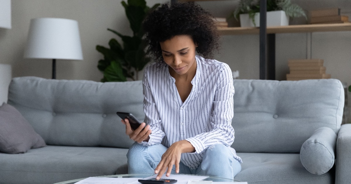 black female sitting on sofa paying domestic bills fees online